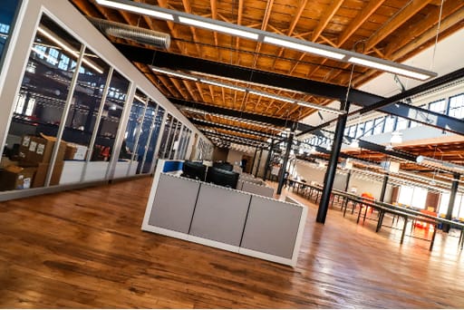 Open office plan with hardwood floors and side glass walled offices at an angle